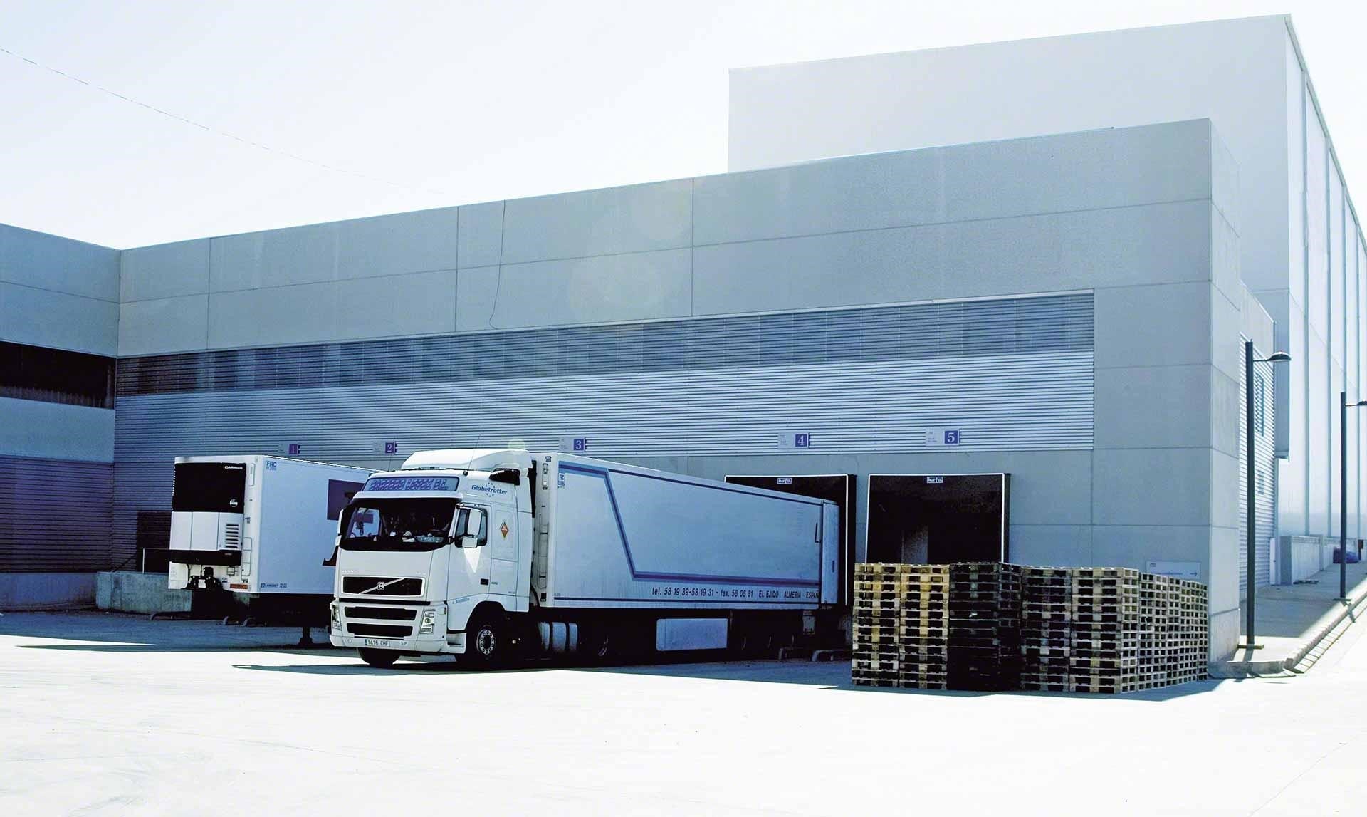 Camiones de mercaderías descargan en el depósito como parte de las operaciones de cross-docking Camiones de mercaderías descargan en el depósito como parte de las operaciones de cross-docking